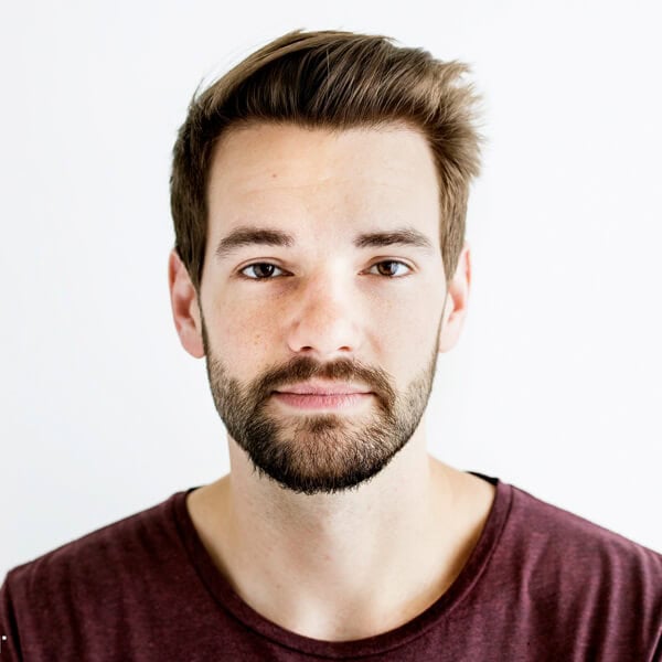 Confident young man with beard and casual attire, representing ENIXEN Group's professional image.