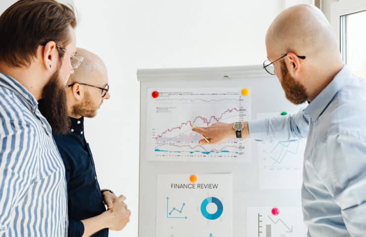Business professionals analyzing financial data on a whiteboard.