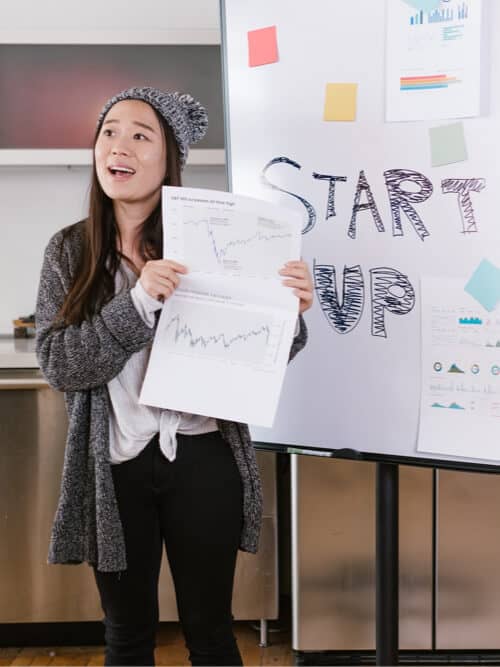 Young woman presenting startup ideas with charts and startup board.