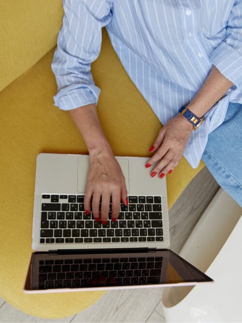Woman working on a laptop with a tablet, showcasing modern technology use.