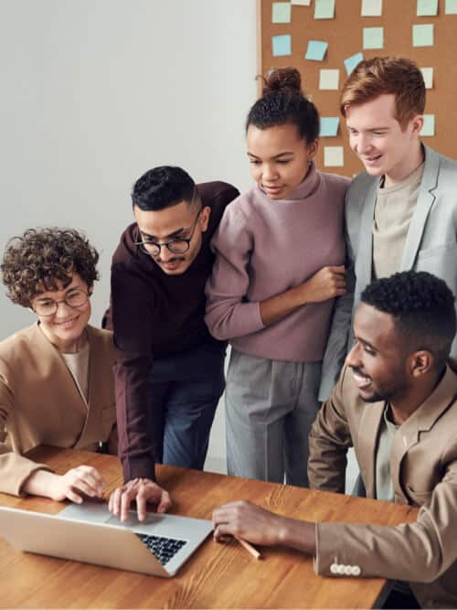 Diverse team working together on a laptop for business strategy.