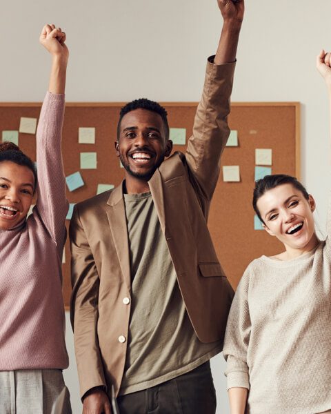 Diverse business team raising fists in victory, symbolizing achievement and teamwork.