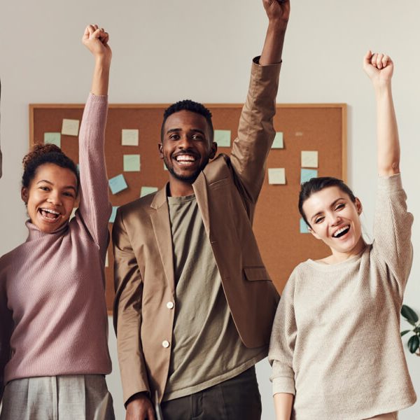 Diverse business team raising fists in victory, symbolizing achievement and teamwork.