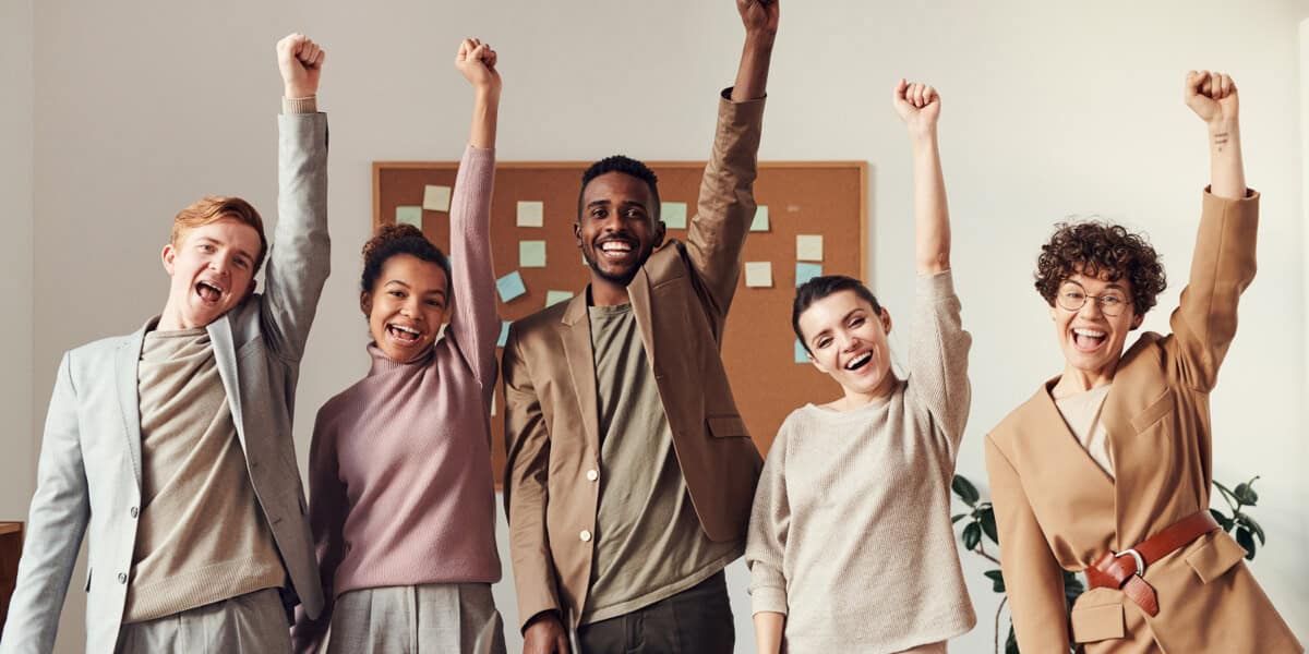 Diverse business team raising fists in victory, symbolizing achievement and teamwork.